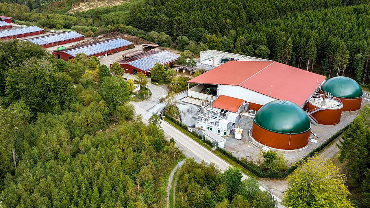 Veduta aerea di un impianto a biogas con due digestori a cupola verde, cogeneratore e tetti con pannelli fotovoltaici